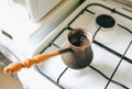 Vintage jezve with freshly brewed coffee on the kitchen. Turkish pot over the oven Royalty Free Stock Photo