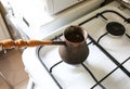 Vintage jezve with freshly brewed coffee on the kitchen. Turkish pot over the oven Royalty Free Stock Photo