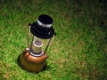 Vintage kerosene oil lantern lamp burning with a soft glow light On the green lawn at night.