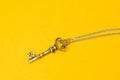 Vintage key with silver chain isolated on yellow background