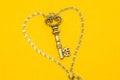 Vintage key with silver chain isolated on yellow background