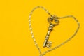 Vintage key with silver chain isolated on yellow background