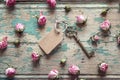 Vintage key with a tag and a little pink roses on an old wooden Royalty Free Stock Photo