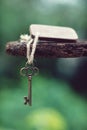 Vintage key with wooden home keyring hanging on old wood plank with blur green garden background, copy space Royalty Free Stock Photo