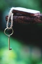 Vintage key with wooden home keyring hanging on old wood plank with blur green garden background, copy space Royalty Free Stock Photo