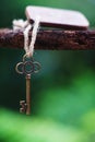 Vintage key with wooden home keyring hanging on old wood plank with blur green garden background, copy space Royalty Free Stock Photo