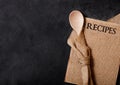 Vintage kitchen wooden utensils with linen recipes board on black stone table background. Top view. Royalty Free Stock Photo