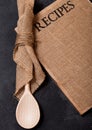 Vintage kitchen wooden utensils with linen recipes board on black stone table background. Top view. Royalty Free Stock Photo