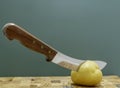 A vintage knife chopping a potato.