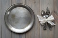 Vintage knife, spoon and fork on a metal plate on a gray wooden background.