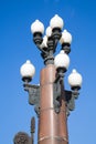 Vintage lamps in the form of a vase located on a column of brown granite against the blue sky. Royalty Free Stock Photo