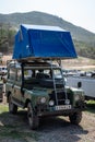 Vintage Land Rover Santana Series III in green with a tent on the roof rack