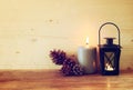 Vintage Lantern with burning Candle and pine cones on wooden table. filtered image. Royalty Free Stock Photo