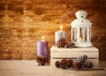 Vintage Lantern with burning Candle and pine cones on wooden table. filtered image Royalty Free Stock Photo