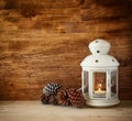 Vintage Lantern with burning Candle and pine cones on wooden table. filtered image. Royalty Free Stock Photo