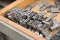 Vintage lead letterpress printing blocks against a weathered wooden drawer background with bokeh