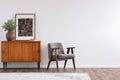 Vintage living room interior with retro furniture and poster, real photo with copy space on the white wall Royalty Free Stock Photo