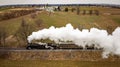 Vintage locomotive train chugging along railroad tracks in a scenic countryside setting