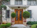 A vintage luxury house facade with ornate natural wooden door, garden and potted flowers. Royalty Free Stock Photo