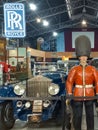 Vintage luxury 1929 Rolls Royce open tourer flanked by a British guard. Logo and brand.