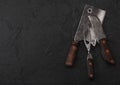 Vintage meat knife and fork and hatchet on black table background. Butcher utensils. Space for text Royalty Free Stock Photo