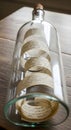 Vintage message in a bottle with script on old paper, corked and on a wooden table Royalty Free Stock Photo