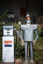 Vintage metal mannequin wearing a formal suit standing beside a classic gasoline pump