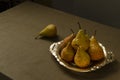 Vintage metallic plate full of yellow pears on the table and tablecloth