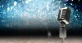 Vintage microphone on a stand over blue sparkling background, performance and holiday concepts Royalty Free Stock Photo