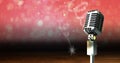 Vintage microphone on a stand over red sparkling background, performance and holiday concepts Royalty Free Stock Photo