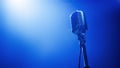 Vintage microphone stands alone under spotlight in dimly lit blue stage Royalty Free Stock Photo