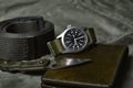 Vintage military watch with nato strap and tactical knife on army green background, Classic timepiece mechanical wristwatch