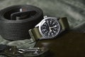 Vintage military watch and tactical belt on army green background, Classic timepiece mechanical wristwatch