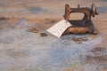 Vintage mini sewing machine with scissors, buttons and fabric on rustic background Royalty Free Stock Photo
