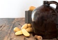 Vintage moonshine jug on a rustic wooden table with potatoes and corn cob cork