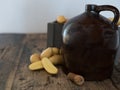 Vintage moonshine jug on a rustic wooden table with potatoes and corn cob cork