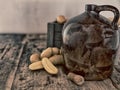 Vintage moonshine jug on a rustic wooden table with potatoes and corn cob cork