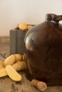 Vintage moonshine jug on a rustic wooden table with potatoes and corn cob cork