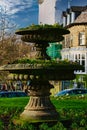 Vintage moss-covered fountain in a sunny park with blurred background of trees and buildings in Harrogate, England