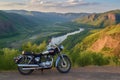 vintage motorbike parked at a scenic viewpoint overlooking a valley