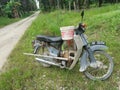 Vintage Motorcycle park outskirt of the plantation carrying long handle Hoe