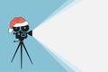 Vintage movie projector with Santa Claus hat. Cinema movie festival poster. Cinema background. Film camera projecting a beam of
