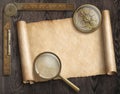 Vintage nautical compass and loupe on table with treasure map scroll Royalty Free Stock Photo