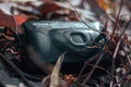 An vintage Nikon EF 100 camera in the middle of a group of fallen leaves in the ground.