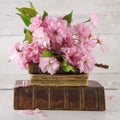 Vintage novel books with bouquet of cherry blossom flowers on white wood background in light pastel colors