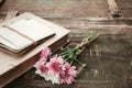 Vintage novel books with bouquet of flowers on old wood background