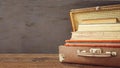 Vintage old classic travel leather suitcases with stack of old books and albums. Travel luggage concept. Retro toning filtered moc Royalty Free Stock Photo