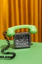 Vintage old clock with an old-fashioned rotary phone on a table in a living room with a background of curtains Royalty Free Stock Photo