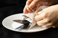 Vintage old fork and knife in napkins and hands tie a rope bow on a napkin, lie on a plate on a black tablecloth on the Royalty Free Stock Photo