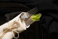 Vintage old fork and knife wrapped in a napkin lie on a black plate on a black background, word serving Royalty Free Stock Photo